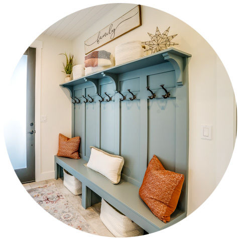 An entryway with a decorative bench, pillows, and coathooks