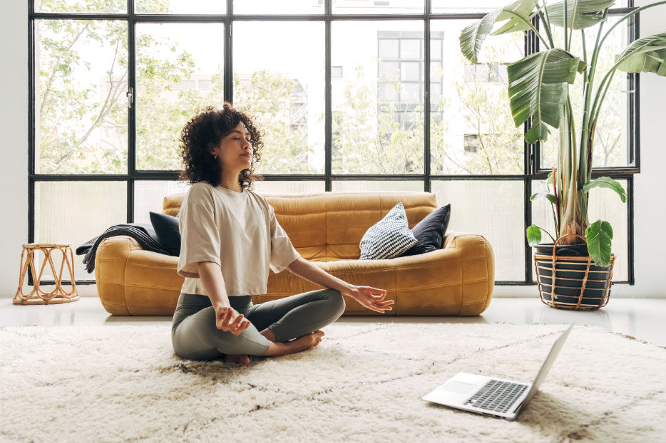 A woman sitting in a yoga pose on a plush rug.